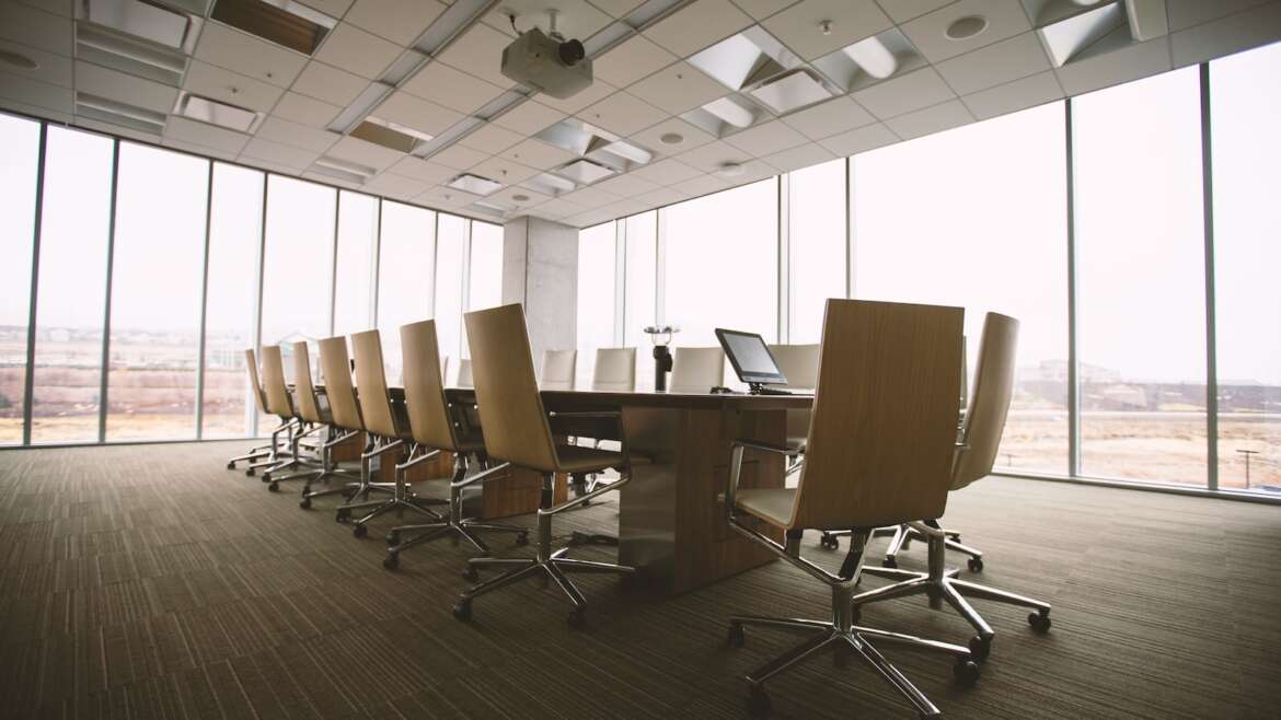 oval brown wooden conference table and chairs inside conference room